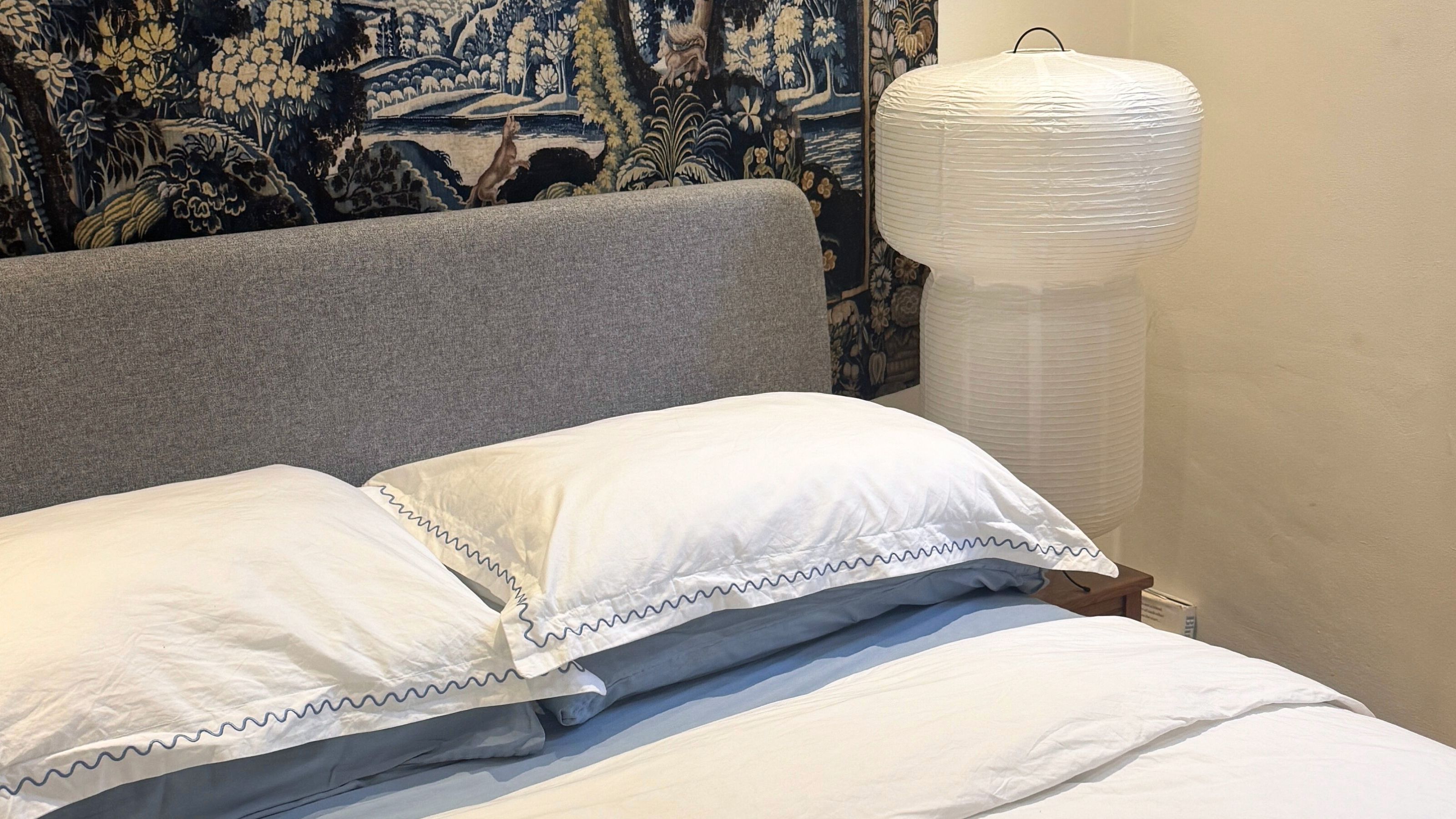 White Christy Bedding with gray headboard, paper lantern, tapestry on the wall