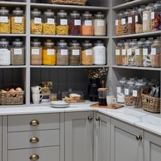 grey pantry with open shelving lined with glass storage jars with labels