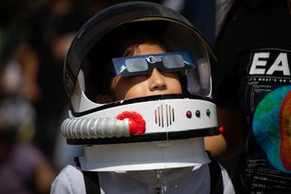 child wearing astronaut costume and solar eclipse viewing glasses