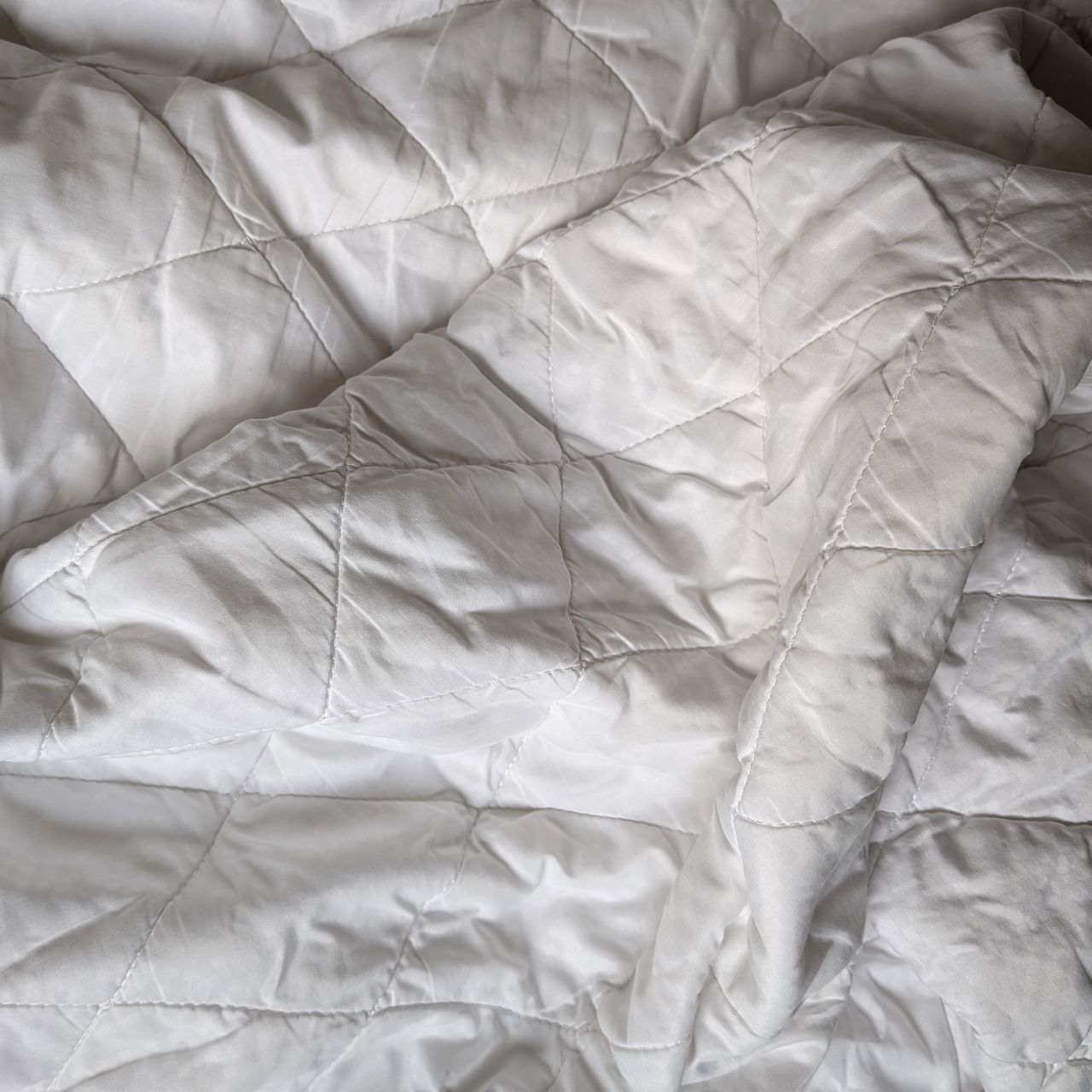 Dunelm mattress protector draped over a bed and slightly unfolded.