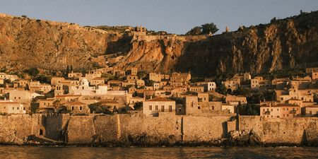 Small stone houses on the coast at sunset, with cliffs in the background