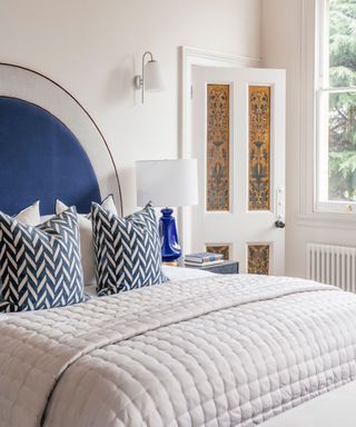 Art Deco bedroom with a curved blue velvet headboard