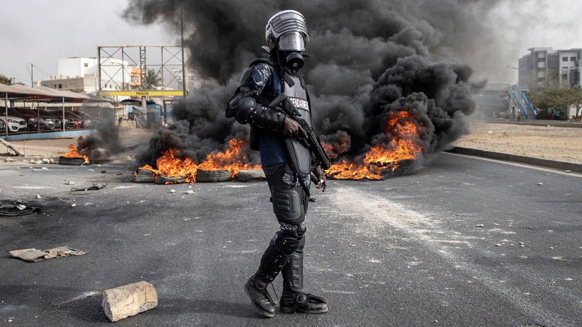 A Senegalese gendarme standing near burning tyres