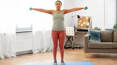 woman does lateral shoulder raise exercise at home
