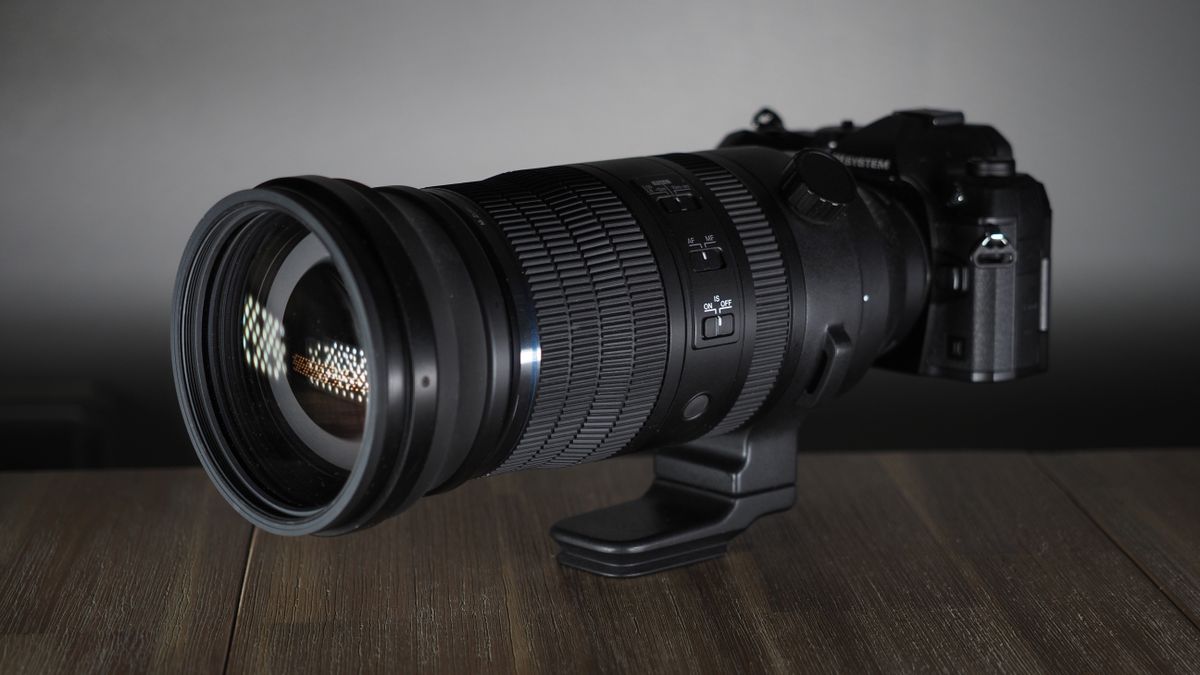 OM System M.Zuiko 150-600mm f/5.0-6.3 IS lens, mounted to an OM System OM-1 Mark II, on a wooden surface lit with moody lighting