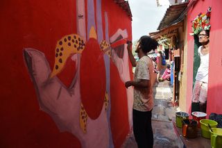 A man looks on as an artist paints a wall of a slum hutment at the Asalpha village in Mumbai on December 17, 2017. With an aim to alter the perspective the world has of urban slums city artis