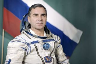 man in white and blue spacesuit with Russian flag in background