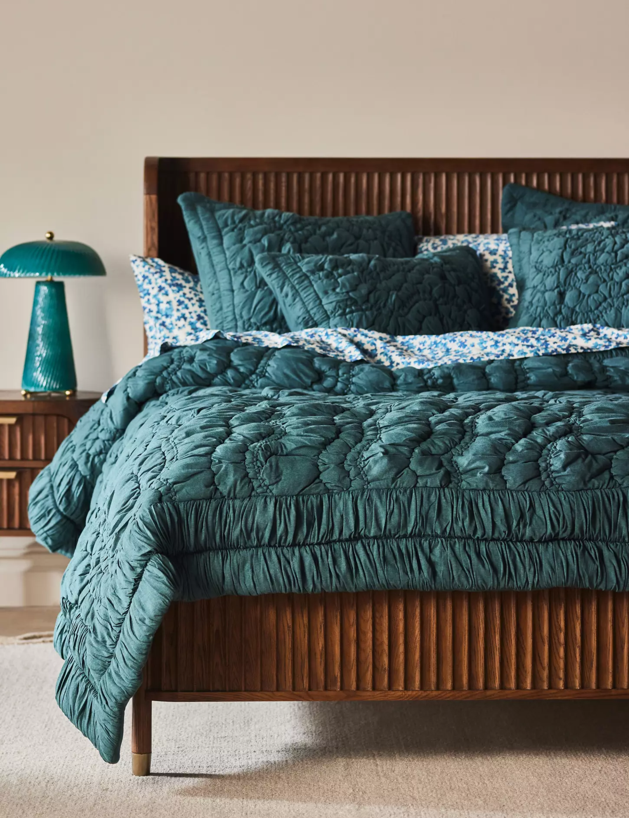 Emerald green floral-embroidered bedding set styled atop of a fluted bed frame