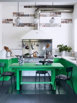 green and white kitchen with black painted floor, green table green painted units and white walls