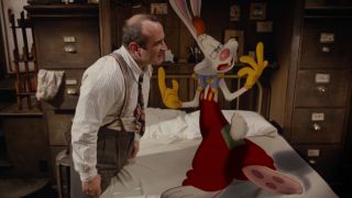 Bob Hoskins stands angrily listening to Roger Rabbit as he stands on his bed in Who Framed Roger Rabbit.