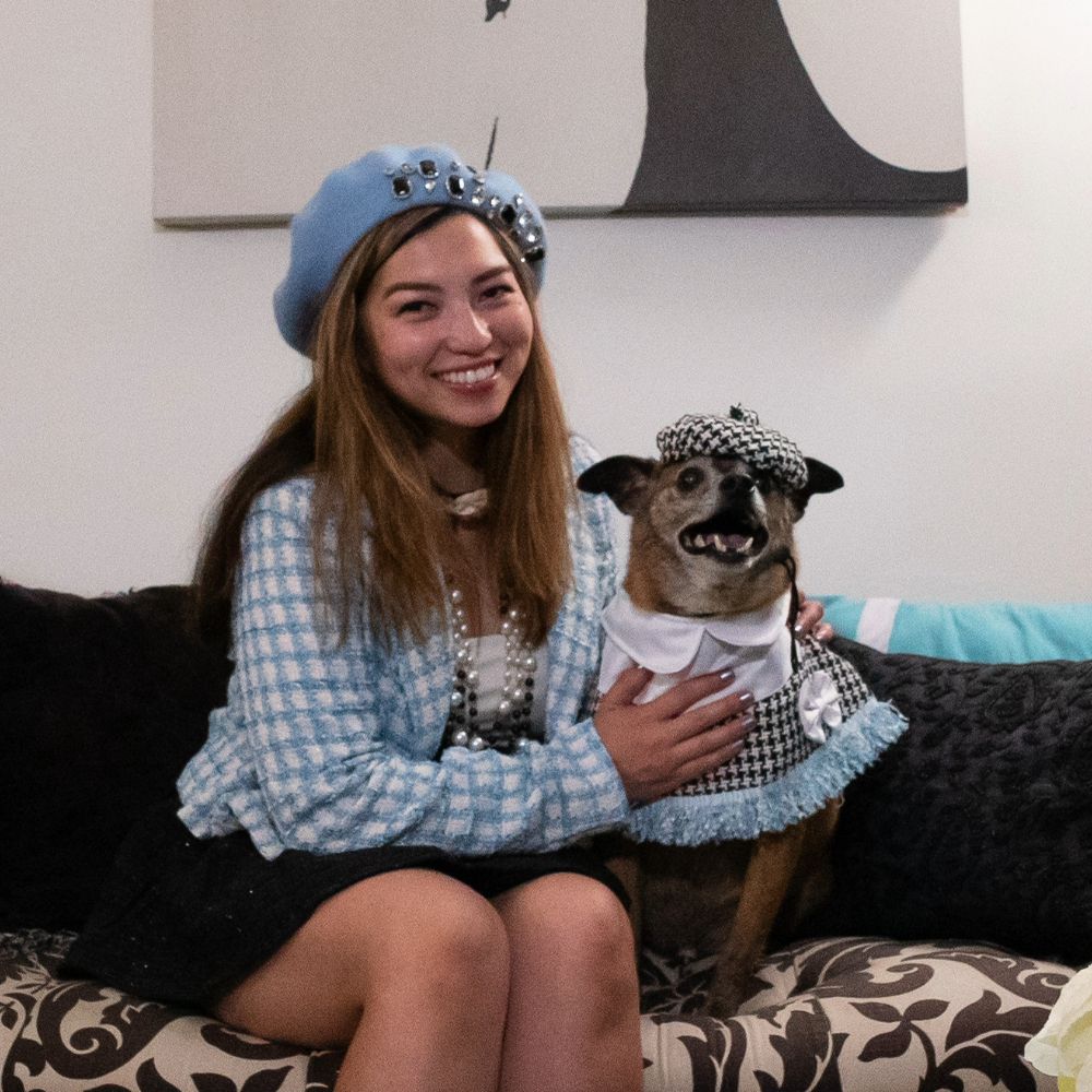 Sarah Nunez sitting next to her dog Duke, both wearing matching tartan outfits and berets