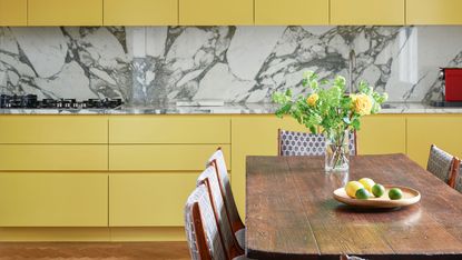 a yellow kitchen with a marble backsplash