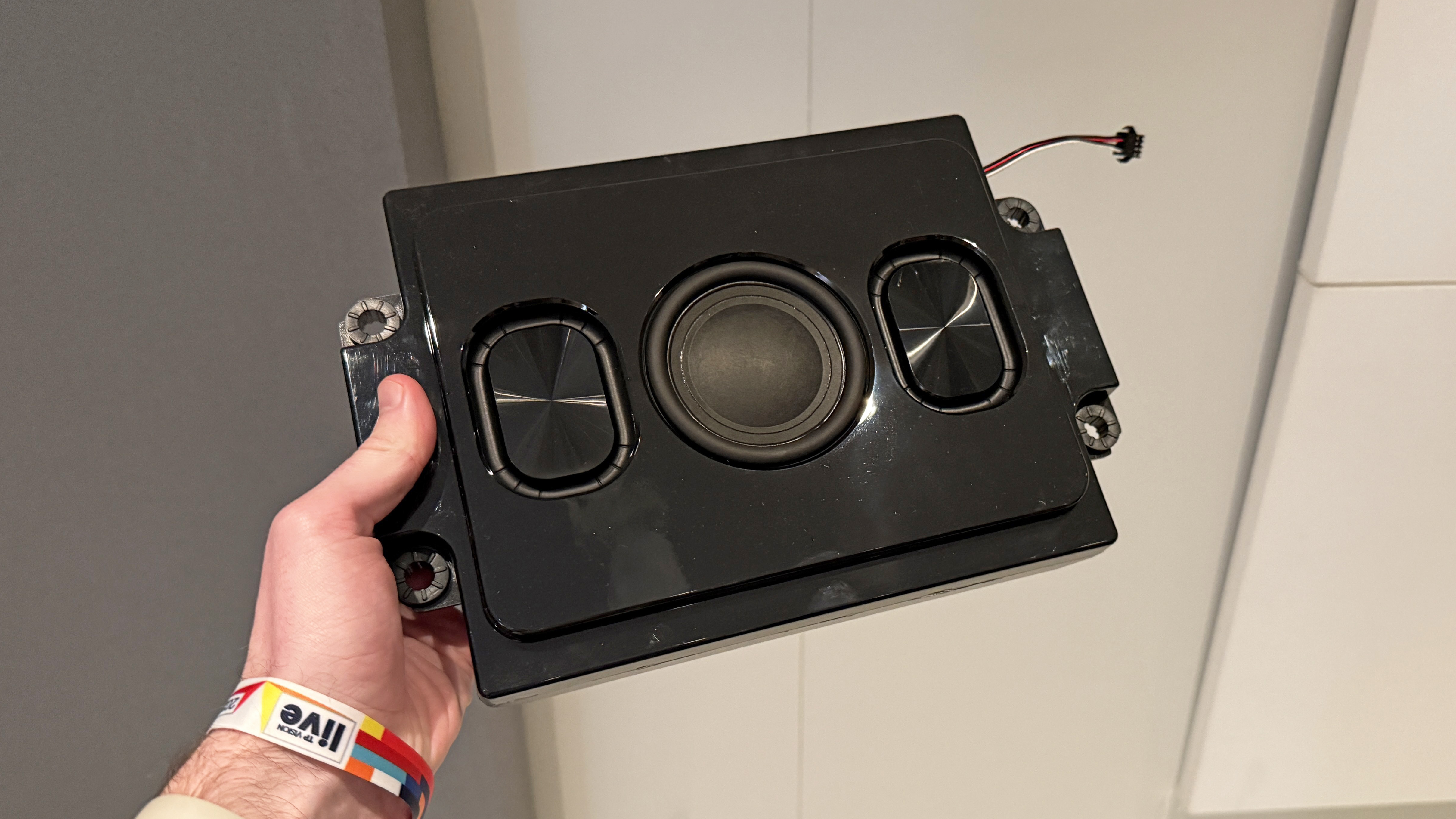 The Philips OLED+910 TV's bass speaker held in a man's hand