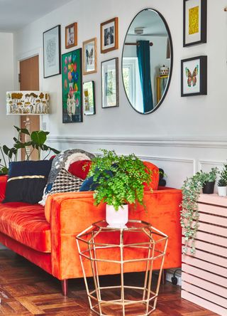 Image of a gallery wall behind an orange sofa in the living room