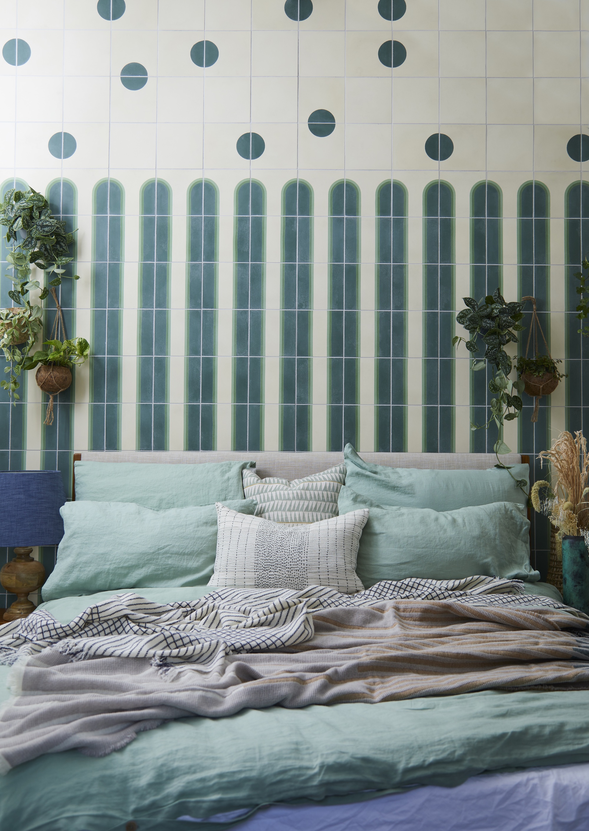 turquoise bedroom with tiled wall, turquoise sheets, and hanging plants