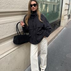 French influencer wears white jeans and white flat shoes outfit on streets of Paris
