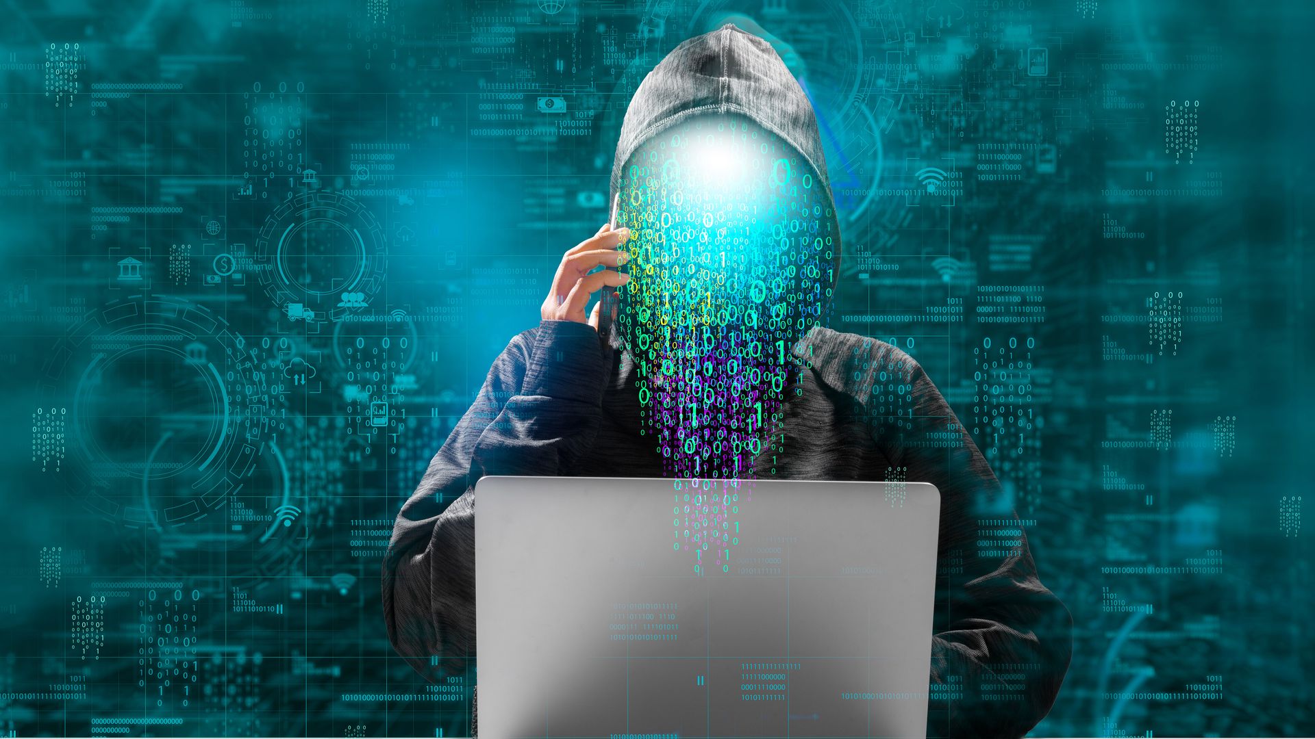 A hooded figure in front of a laptop. Digital symbols obscure his face and appear to be pouring out of his head