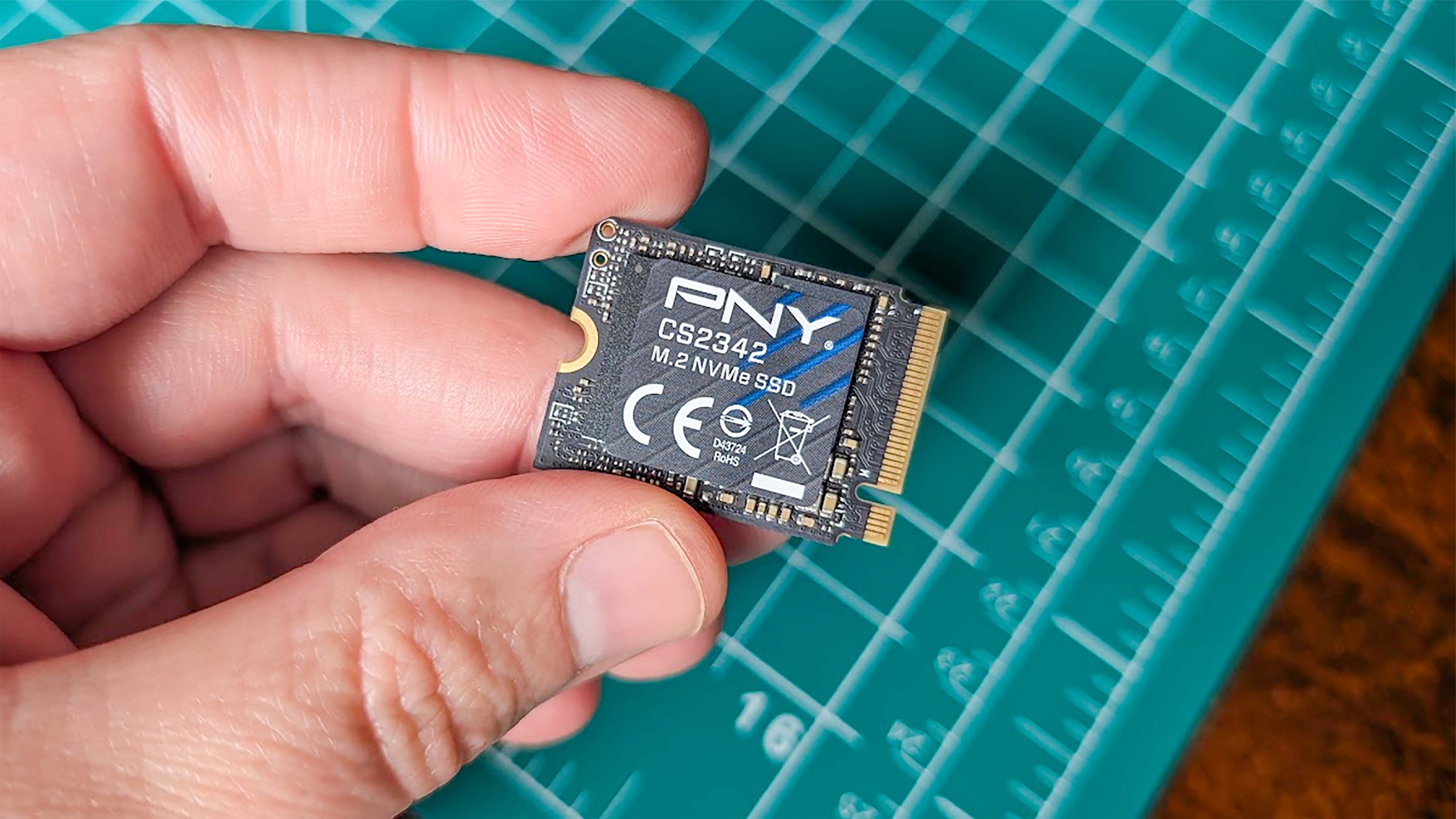 A hand holding a 2TB PNY M.2 2230 SSD.