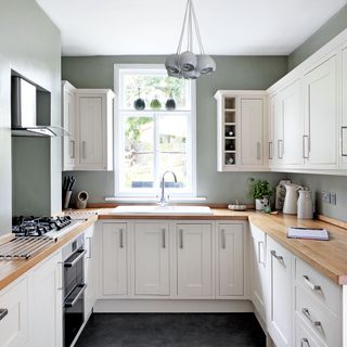 kitchen with white cabinet and wooden platform with white window and microwave