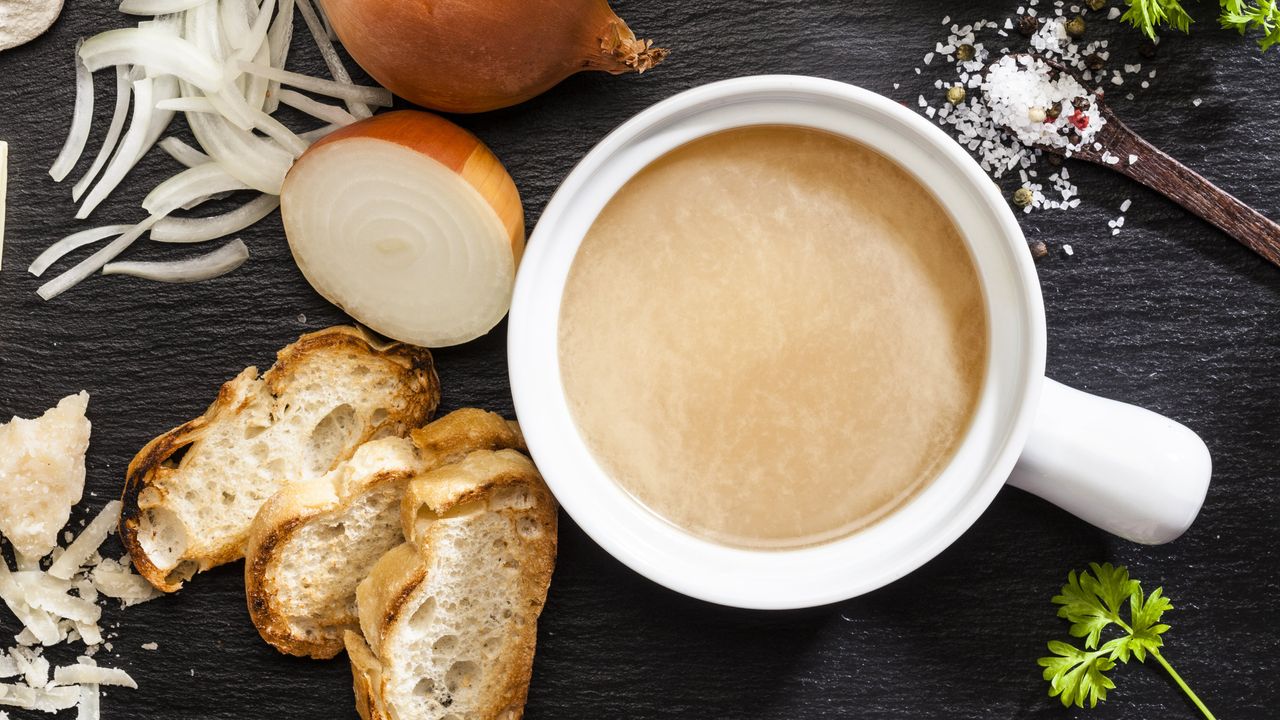 Cheese, onion and parsley soup in a bowl with ingredients