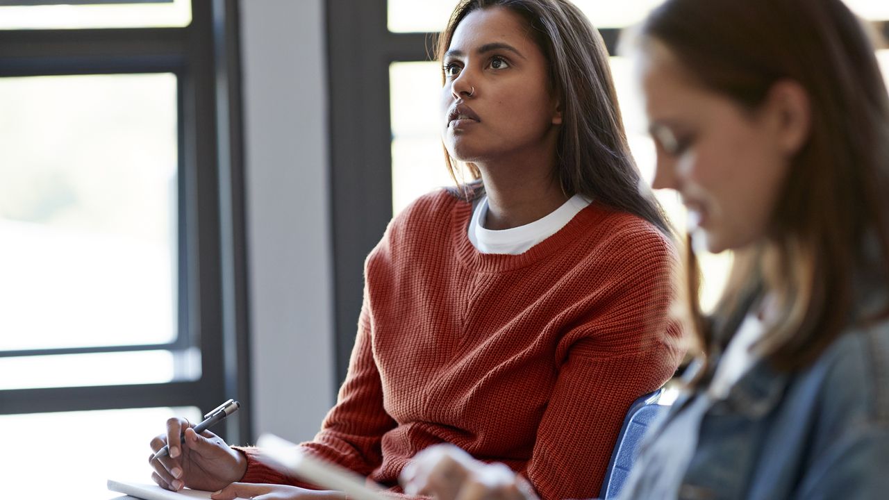 Adult female students take notes in class.