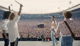 Rami Malek on stage facing concert crowd in Bohemian Rhapsody