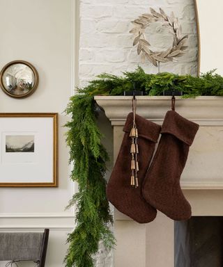 Winter mantel decorated with foliage, stocking and metal wreath ornament