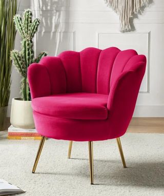 Deep jewel tone pink scallopped chair with gold legs on cream rug and cactus in background