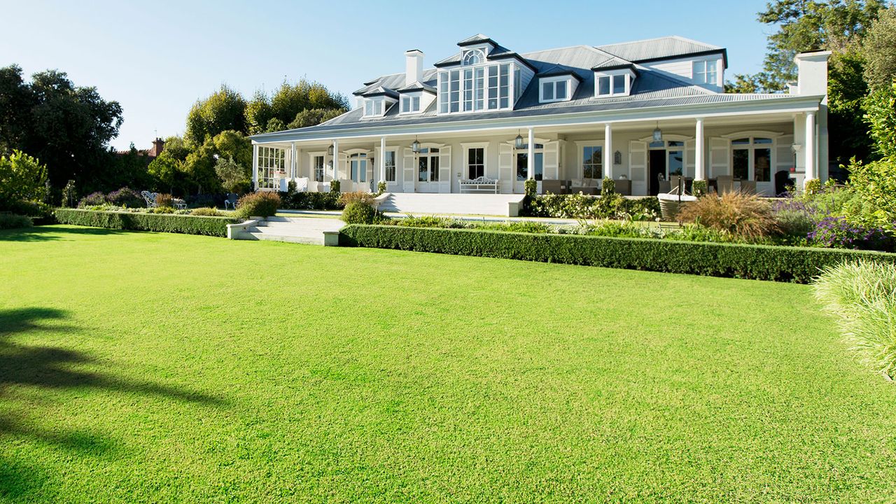 lawn area in the sunshine at the rear of a large house 