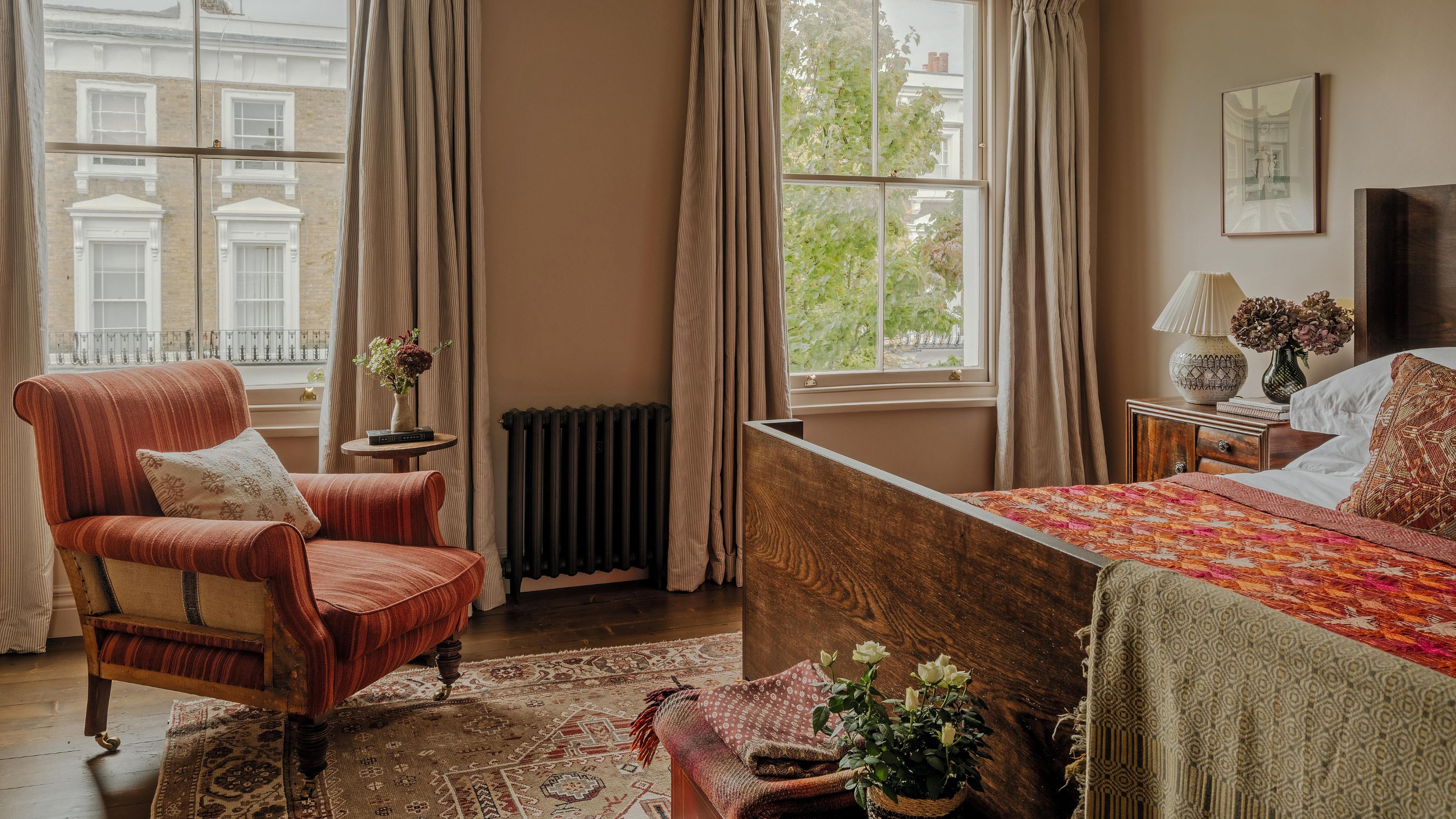 a dusty pink london bedroom with georgian windows and an antique wooden bed