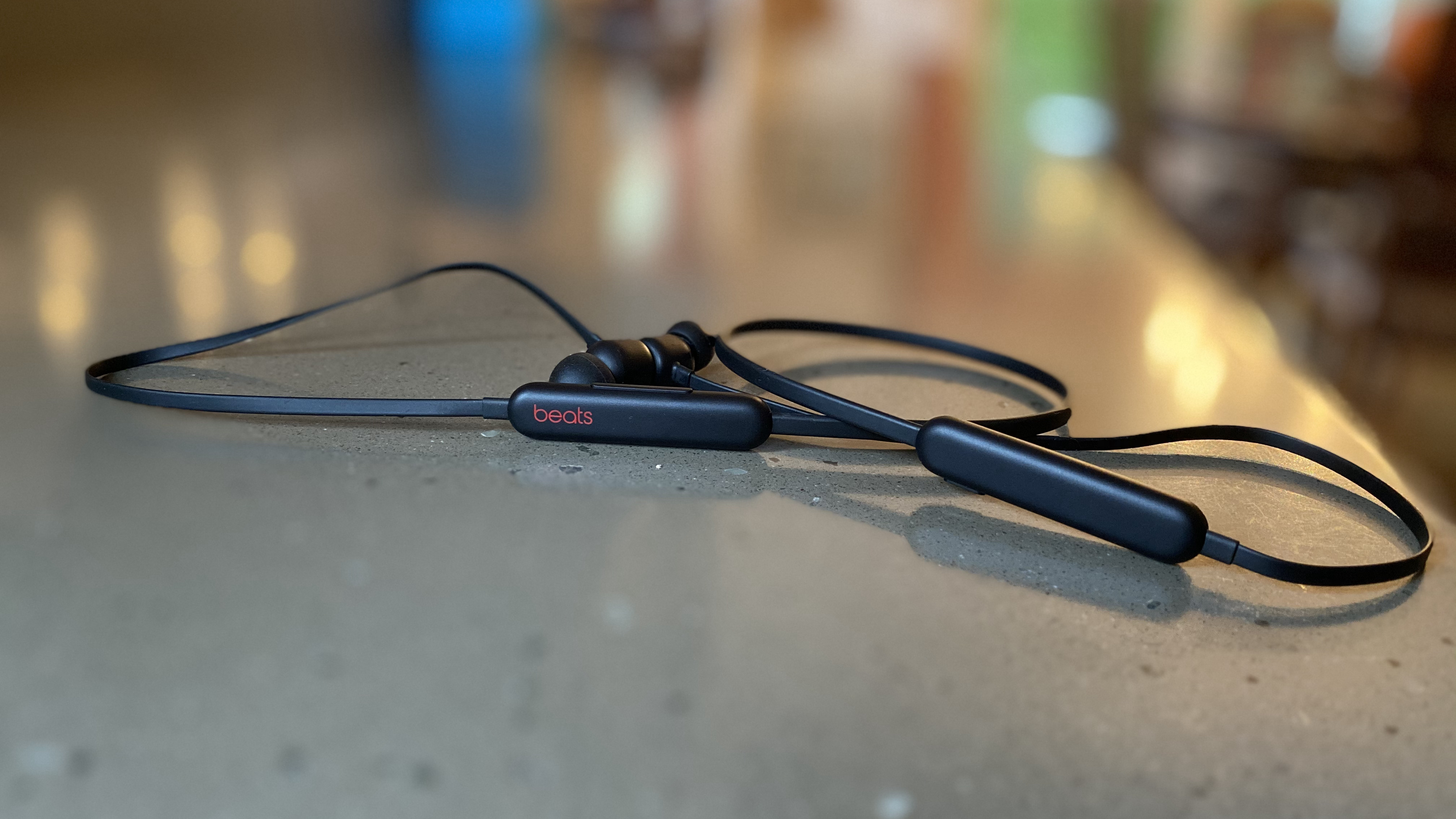 Gambar earphone nirkabel Beats Flex berwarna hitam di atas permukaan marmer