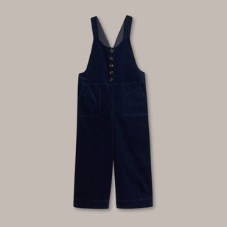 A cutout of White Stuff Navy Cord dungarees shot against a beige background