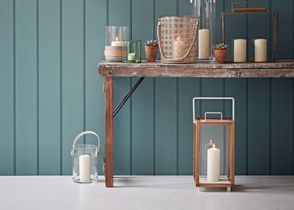 pillar candles on a table in front of a blue wall