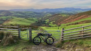Bikepacking bike by gate in Welsh panorama