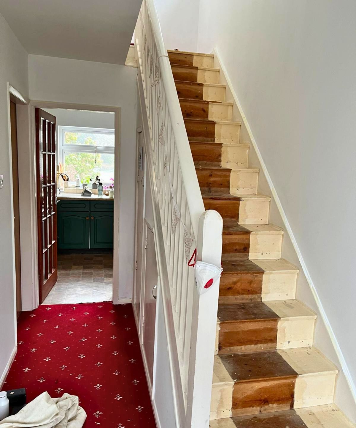 A mid-renovation staircase showing carpet stripped back revealing raw mismatched wooden treads.