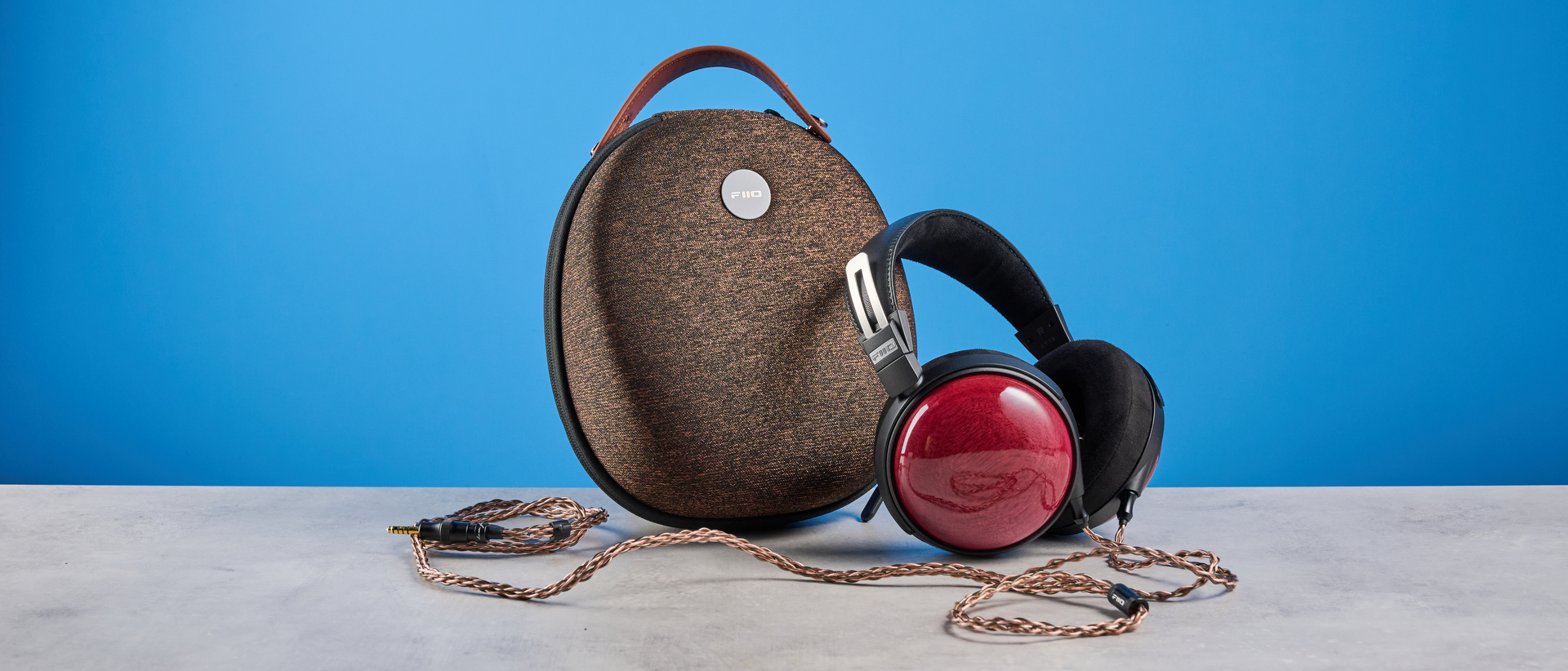 the fiio ft13 wired headphones with wood cups and copper cable photographed against a blue background