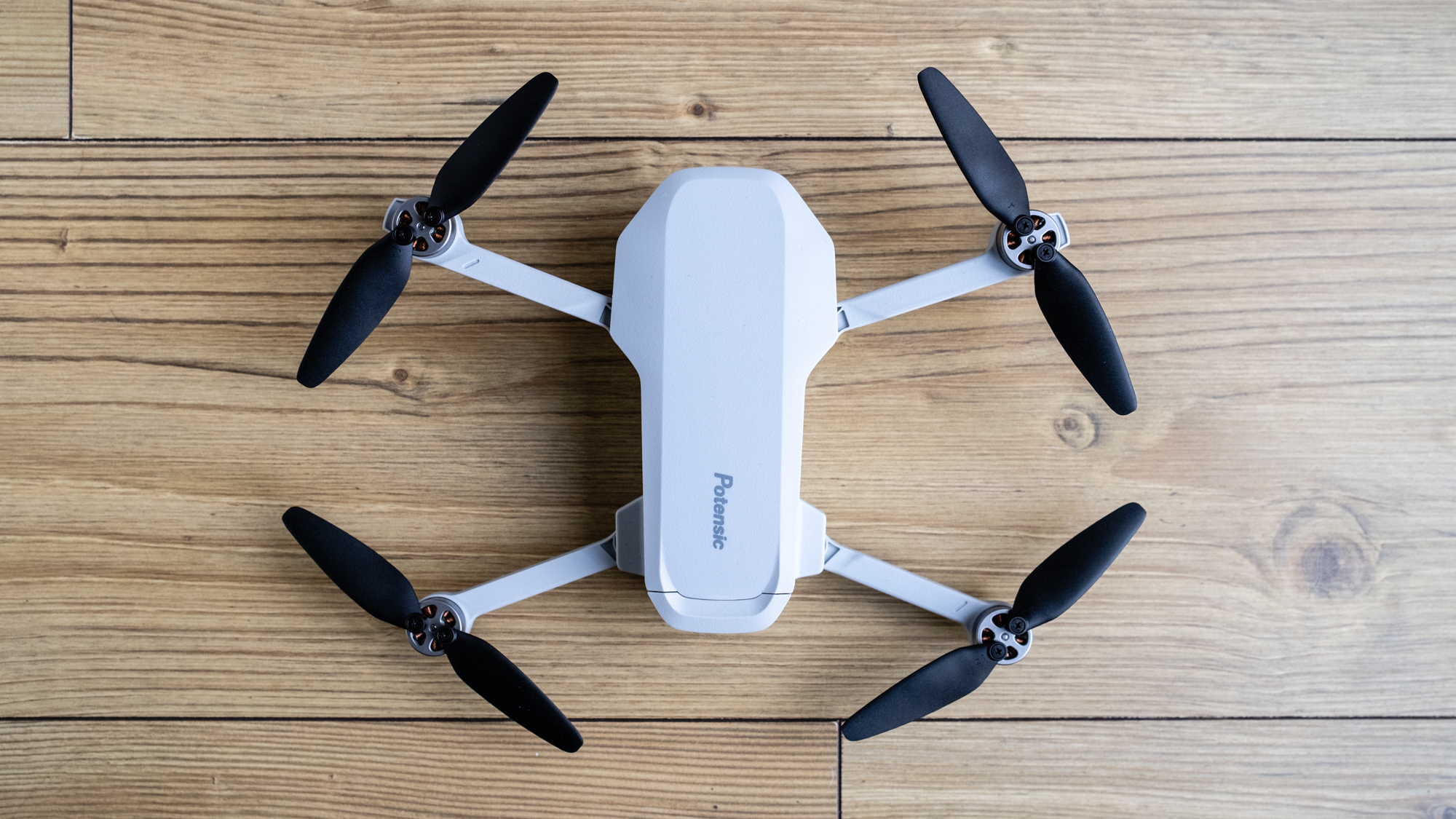 Potensic Atom SE drone unfolded on a wooden floor
