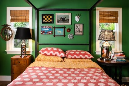 A green bedroom and bed with red and white spotted bedding, and a photo wall above the headboard