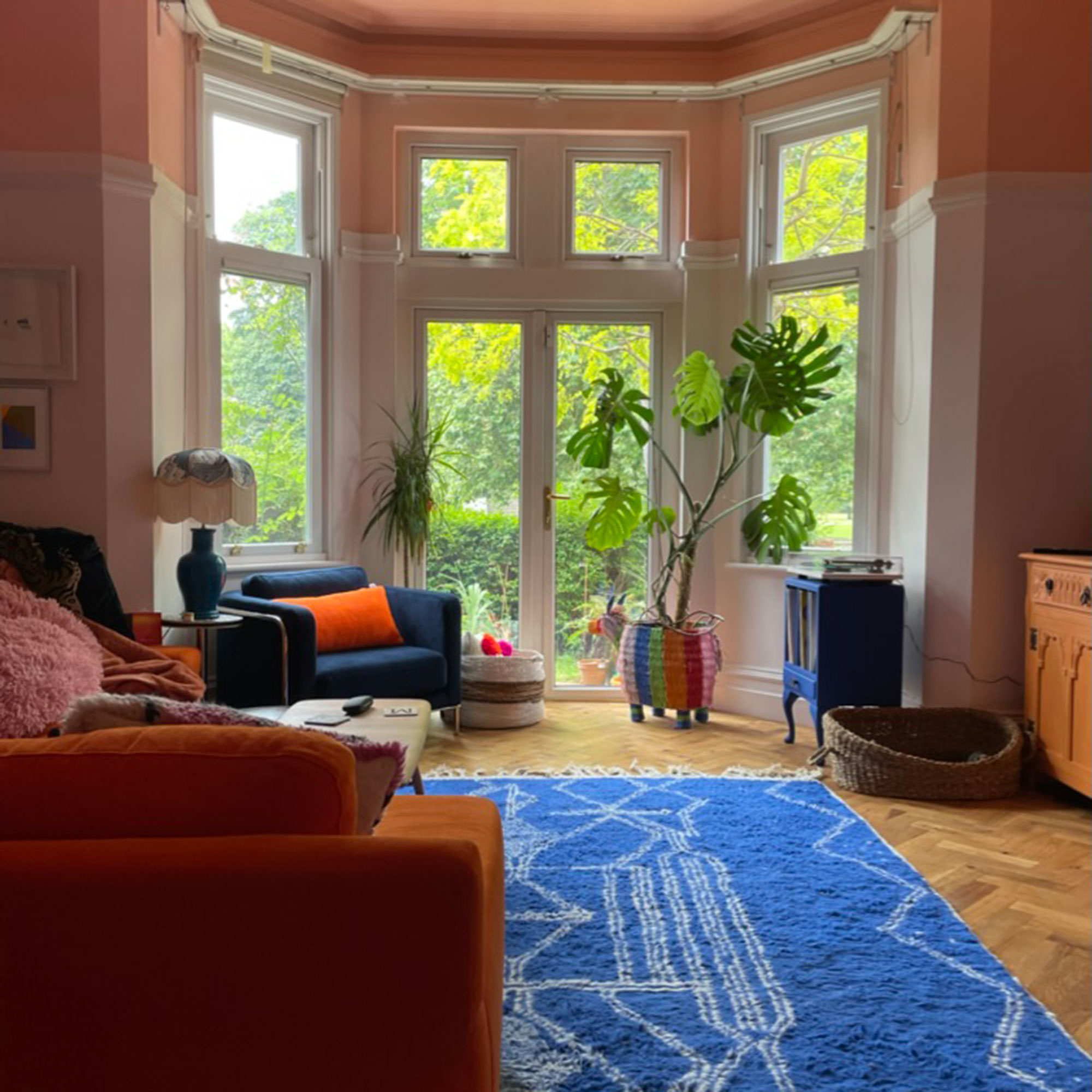 Pink and white living room with blue Berber rug on top of wooden floor