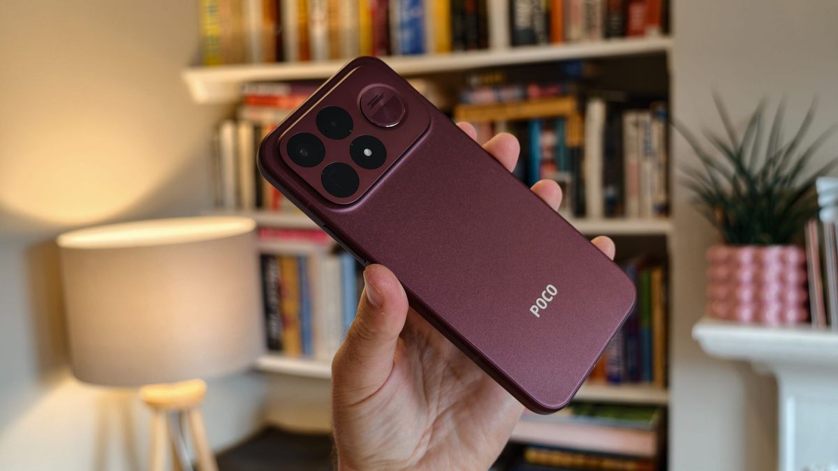 The Poco F9 Ultra being held in the hand and resting on a table