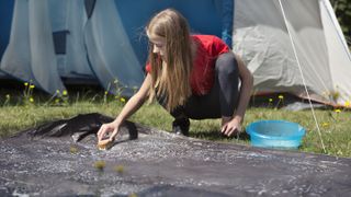 types of tent: girl cleaning a groundsheet