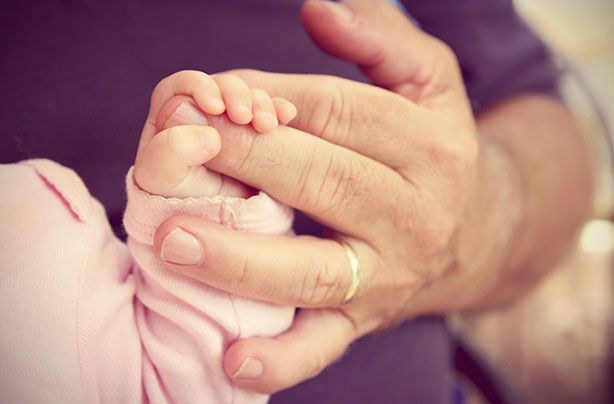 A baby&#039;s hand holding an adult&#039;s hand.