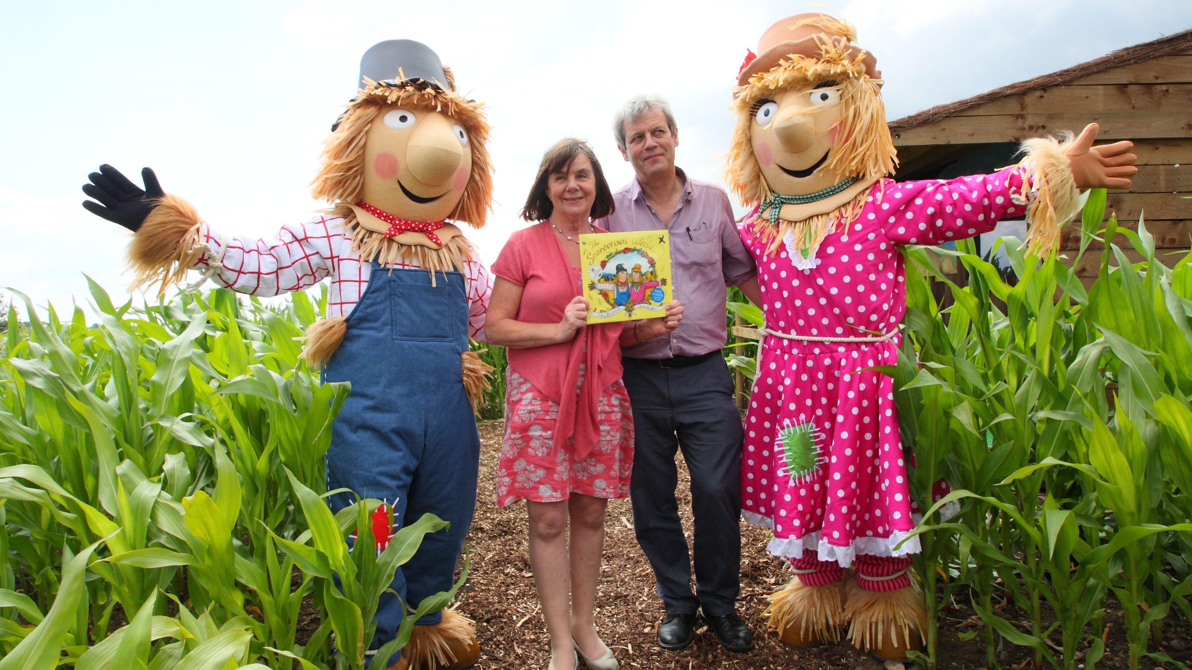 Julia Donaldson and Axel Scheffler standing next to scarecrows and holding up a copy of their book, The Scarecrows&#039; Wedding 