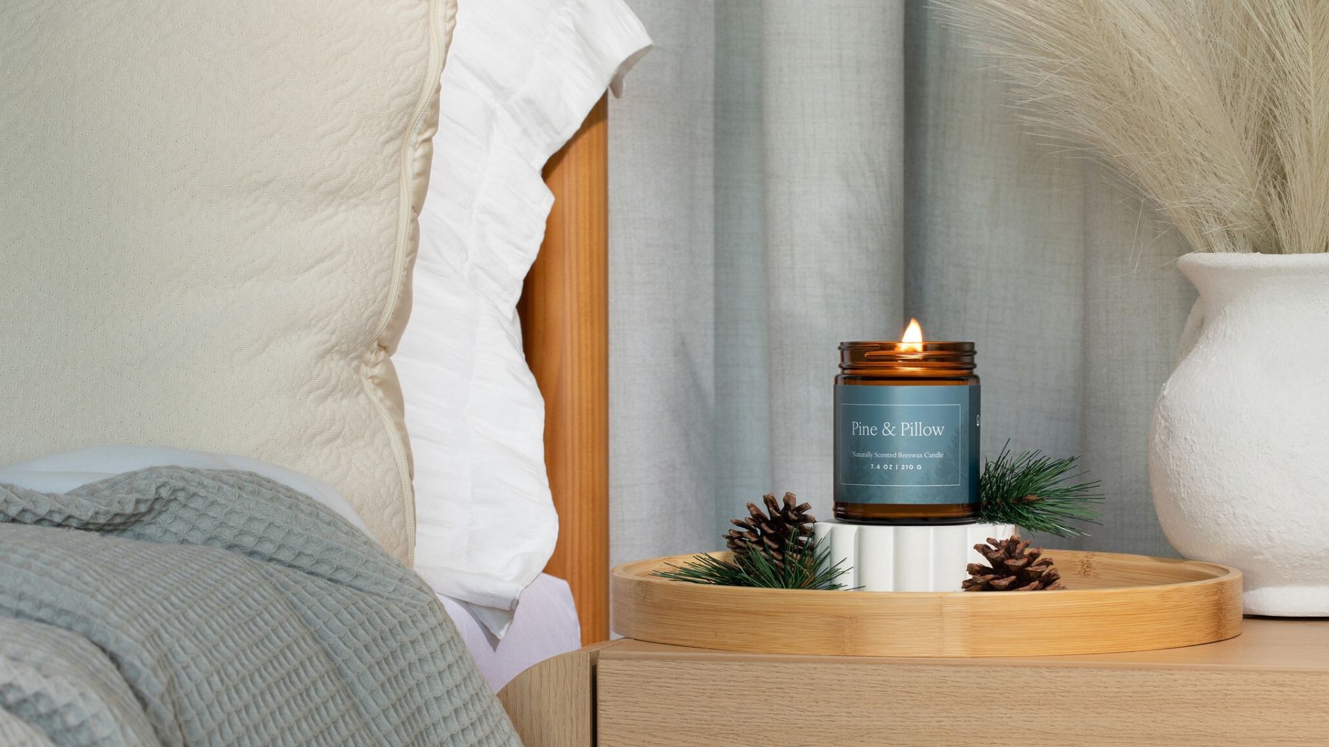 The Naturpedic Pine &amp;amp; Pillow Candle on a wooden nighstand.