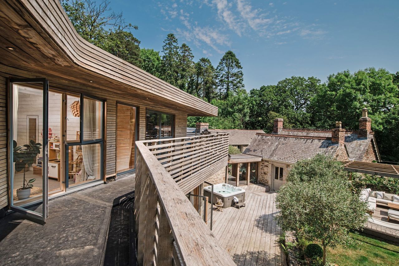 The balcony made from wood looks down on the front garden and the neighbouring stone house