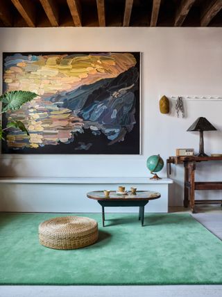 Green rug in a living space with large landscape artwork