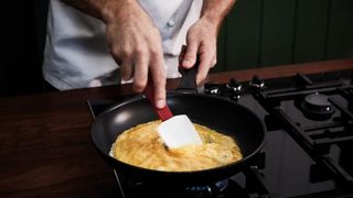 Hands using plastic spatula to lift omelette from the skillet