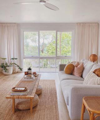 A living room with a gray couch coffee table, and large windows
