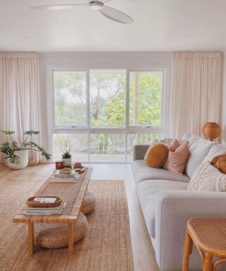 A living room with a gray couch, coffee table, and large windows