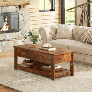 A medium-toned wood coffee table with shelves on the bottom in front of a white couch